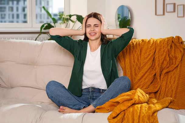 Young woman suffering from headache on sofa at home. Hormonal disorders - Foto, Bild