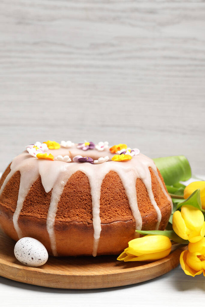 Delicious Easter cake decorated with sprinkles near egg and beautiful tulips on white wooden table. Space for text - Fotografie, Obrázek