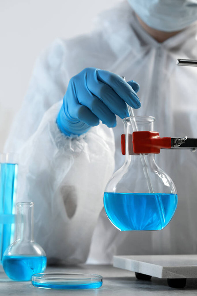 Scientist taking sample of light blue liquid in laboratory, closeup - Фото, зображення