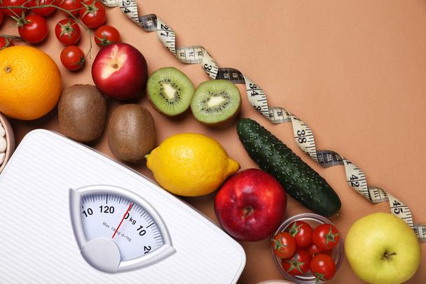 Scales, measuring tape, fresh fruits and vegetables on light brown background, flat lay with space for text. Low glycemic index diet - Fotografie, Obrázek