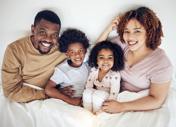 Familie, bed en gelukkig portret van een moeder, vader en kinderen in een slaapkamer in de ochtend. Huis, geluk en glimlach van een moeder, kinderen en papa samen met hechting, ouderzorg en liefde in een huis. - Foto, afbeelding
