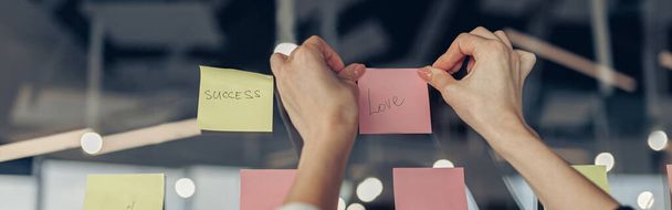 Bizneswoman ręce przyklejają lepkie notatki na tablicy motywacyjnej w biurze. Wysokiej jakości zdjęcie - Zdjęcie, obraz