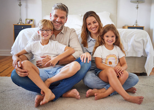 Portrait family, children smile and parents with love for kids on floor in bedroom of house together. Boy and girl siblings happy bonding with mother and father in home with happiness on weekend. - 写真・画像