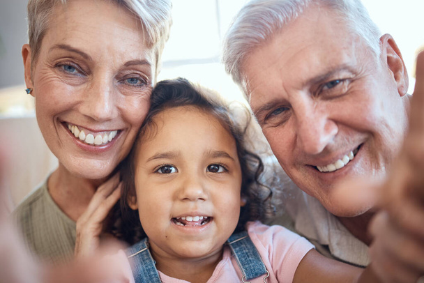 Interracial family, selfie and girl with grandparents at home feeling happy with love and care. Portrait of senior people with an adopted kid bonding together at a house busy with youth care. - Fotoğraf, Görsel