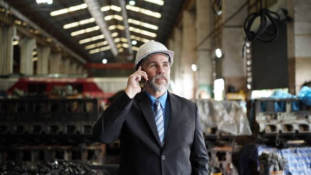 Διευθυντής εργοστασίου ή επιχειρηματίας ιδιοκτήτης σε αποθήκη εργοστάσιο μιλάει στο κινητό τηλέφωνο. Ιστορικό του επιχειρηματικού κλάδου. - Φωτογραφία, εικόνα