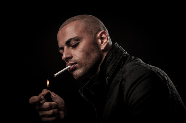 Handsome young man smokes cigarette in darkness - photography of - Fotografie, Obrázek