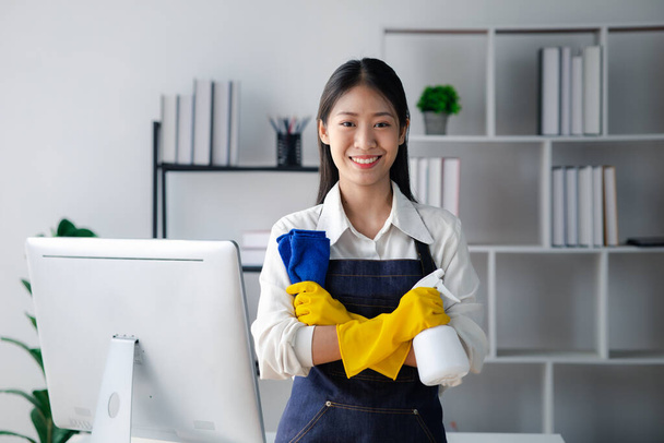 Aasialainen nainen siivoamassa toimistoa, siivoamassa. Säilytä puhtaus organisaatiossa. Toimiston desinfiointi ehkäisee taudinpurkauksia ja ylläpitää hygieniaa. - Valokuva, kuva