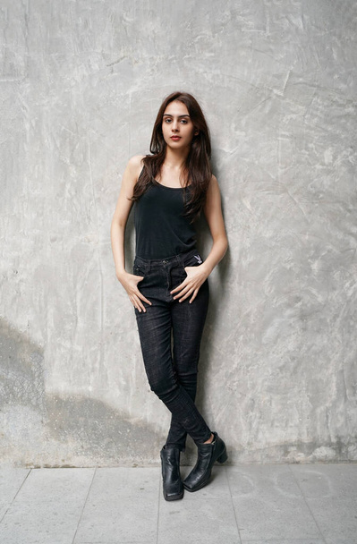 スタジオでのファッションモデル。スタイリッシュなファッショナブルな黒の服で美しいセクシーな女性。壁の背景に黒い服を着て若い豪華なインドの女性ファッションモデル. - 写真・画像