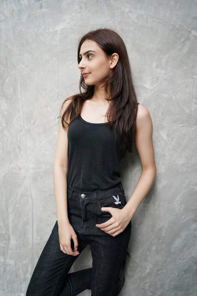 Model im Atelier. Schöne sexy Frau in stilvollen modischen schwarzen Kleidern. Junge hinreißende indische Modedesignerin trägt schwarze Kleidung vor Wandhintergrund. - Foto, Bild