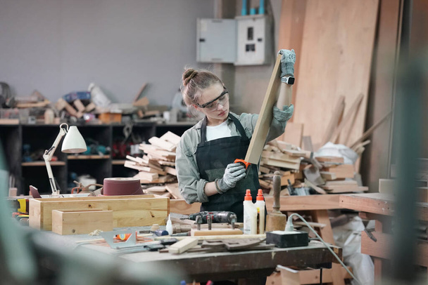 Small business of a young woman. Beautiful young woman worker in a furniture workroom - Fotografie, Obrázek
