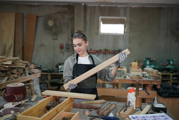 Small business of a young woman. Beautiful young woman worker in a furniture workroom - Valokuva, kuva
