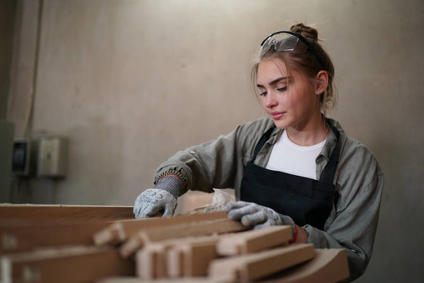 Small business of a young woman. Beautiful young woman worker in a furniture workroom - Фото, зображення