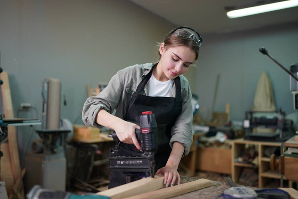 Small business of a young woman. Beautiful young woman worker in a furniture workroom - Foto, afbeelding