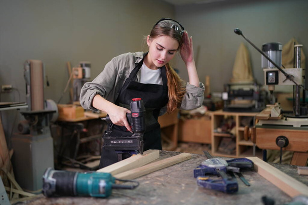 Small business of a young woman. Beautiful young woman worker in a furniture workroom - Foto, Bild