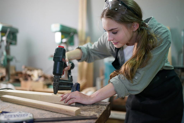 Small business of a young woman. Beautiful young woman worker in a furniture workroom - Photo, Image