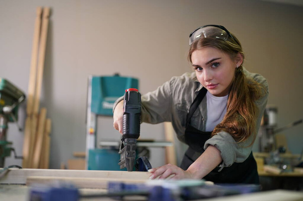 Small business of a young woman. Beautiful young woman worker in a furniture workroom - Photo, Image