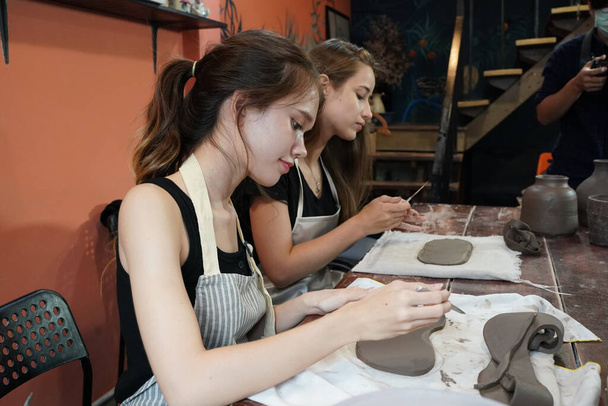 Řemeslnice sedí u stolu a pracuje s hliněnými vázami a keramiky pozadí, majitel firmy - Fotografie, Obrázek