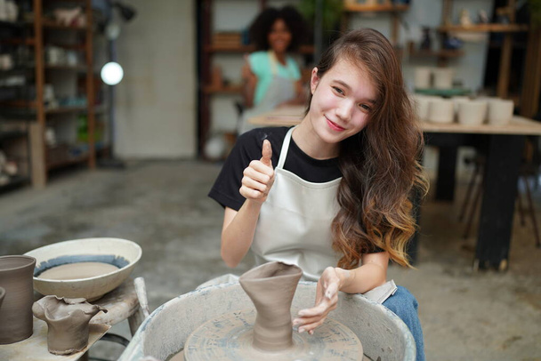 Close-up de bela artesã em avental sentado na loja de cerâmica - Foto, Imagem