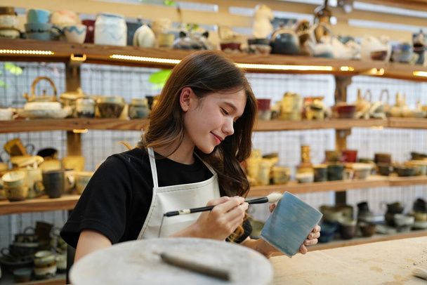 Close-up of beautiful craftswoman in apron sitting at pottery shop - Photo, Image