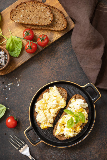 Scrambled eggs on whole grain bread. Homemade breakfast or brunch meal - scrambled eggs. View from above.  - Фото, зображення