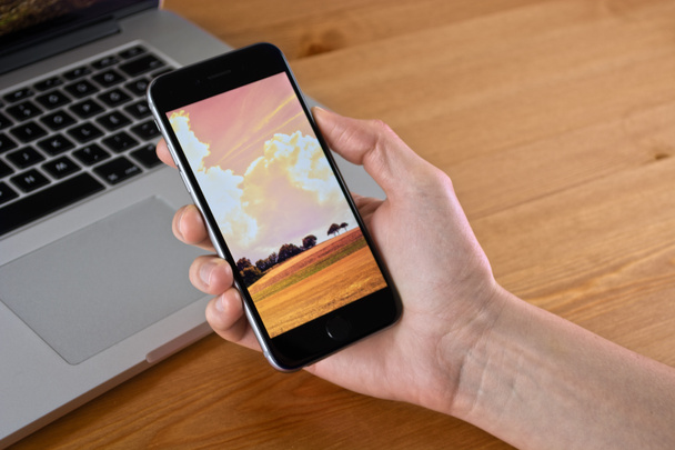 iPhone 6 sostener en la mano con un Macbook
 - Foto, imagen