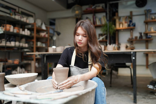 Közelkép a gyönyörű kézműves nő kötényben ül a fazekas boltban - Fotó, kép