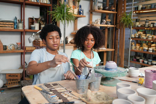 Jonge Afro meisje en jongen in aardewerk workshop, Zakelijk eigenaar.  - Foto, afbeelding