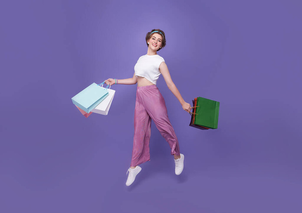 Весела щаслива жінка, насолоджуючись покупками, вона несе сумки і стрибає, щоб отримати останні пропозиції в торговому центрі
. - Фото, зображення