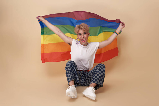 Młodzież azjatycka transgenderowa LGBT z tęczową flagą na ramieniu odizolowana na tle nagich kolorów. duma i koncepcja równości płci. - Zdjęcie, obraz