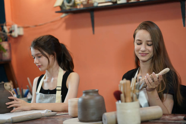 Artesãos sentados à mesa e trabalhando com vasos de argila e cerâmica de fundo, proprietário do negócio - Foto, Imagem