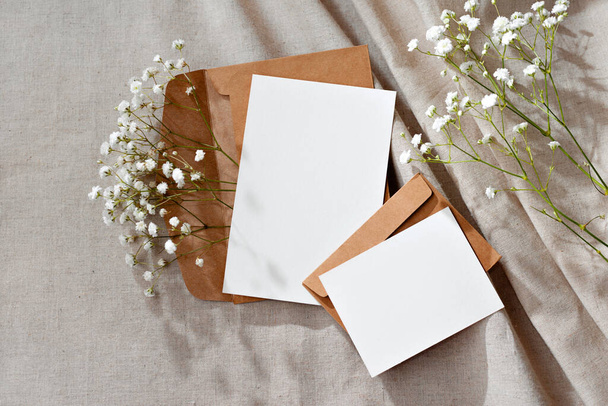 Plantilla estética floral de la marca de fábrica, tarjetas de papel en blanco y sobres sobre un fondo beige neutro, maqueta con espacio para copiar - Foto, Imagen