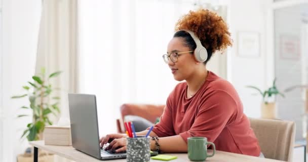 Laptop, Schreibmaschine und schwarze Frau mit Kopfhörern im Home Office für ein Projekt, während sie Musik streamt. Freiberuflerin, Fernarbeiterin und glückliche Frau, die am Computer arbeitet, während sie Radio oder Podcast hört - Filmmaterial, Video