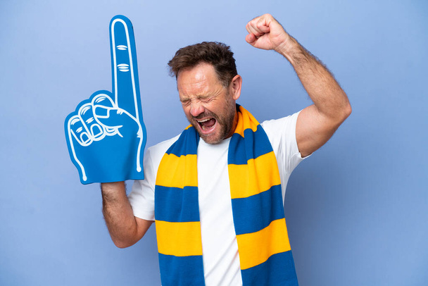 Moyen Age caucasien fan de sport homme isolé sur fond bleu célébrant une victoire - Photo, image