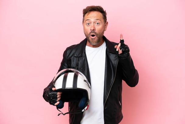 Middle age caucasian man with a motorcycle helmet isolated on pink background thinking an idea pointing the finger up - Photo, Image