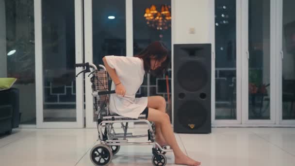 Een vrouw is verlamd van pijn en woede terwijl ze uit haar rolstoel probeert te komen in de woonkamer. - Video