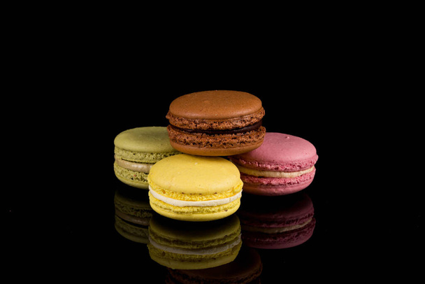 Colorful macaroons over a black background with reflection - Foto, immagini