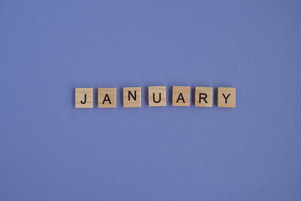 The first month of the year JANUARY -from isolated letters on wooden blocks in natural color, in high resolution. Very Peri background, copy space. Flat lay, step by step, step1 - Photo, Image