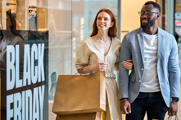 joyful emotional young awesome diverse couple taking part in black friday global sale, enjoyment, happiness. close up photo - Фото, изображение
