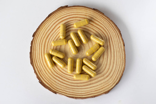 Capsule gialle su fondo di legno e bianco. Farmaci o pillole per la salute dei reni - Foto, immagini