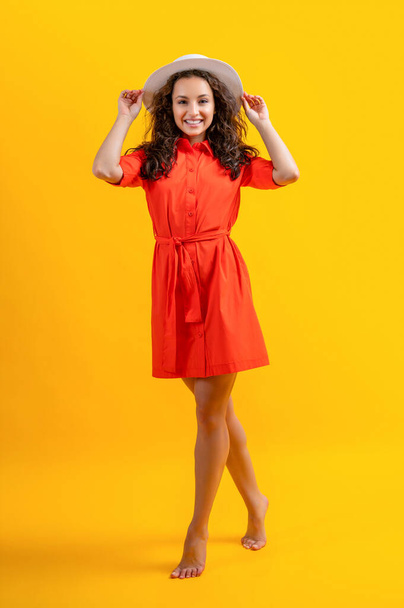 full length of stylish summer woman in studio. stylish summer woman on background. photo of stylish summer woman wearing hat. stylish summer woman isolated on yellow. - Photo, image
