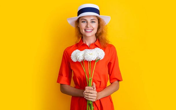 smiling girl with mothers day flowers in studio. girl with mothers day flowers on background. photo of girl with mothers day chrysanthemum flowers. girl with mothers day flowers isolated on yellow. - Foto, Imagem