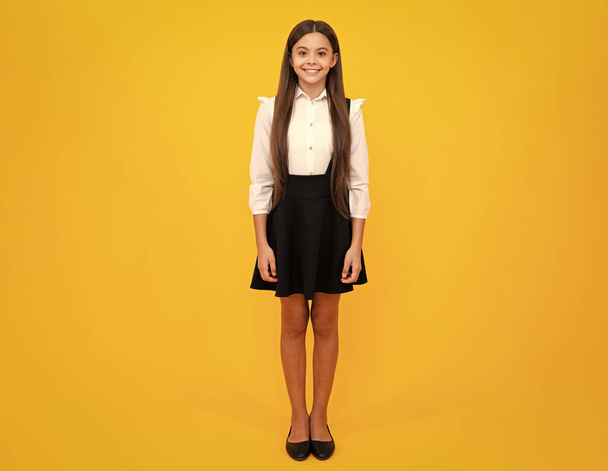 Szkolny mundur. Nastoletnie dziecko dziewczyna casual ubrania pozowanie izolowane na żółtym tle w studio. Koncepcja stylu życia dzieci. Przestrzeń kopiowania makiety - Zdjęcie, obraz