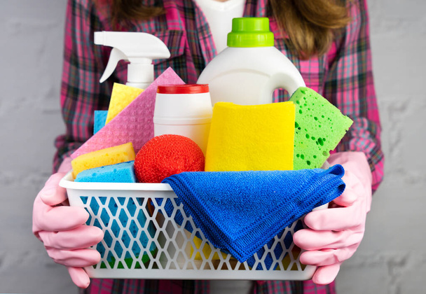 Een jonge vrouw in rubberen handschoenen houdt schoonmakers en wasmiddelen om het huis schoon te maken. Een close-up. Selectieve focus. - Foto, afbeelding