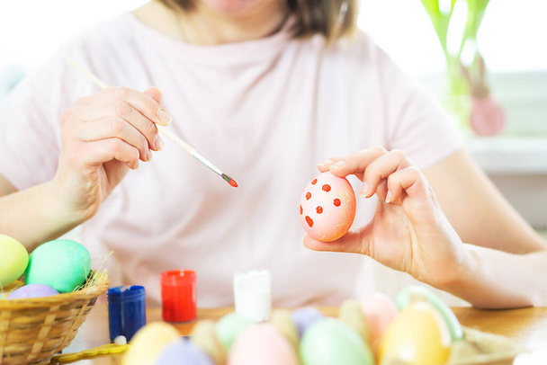 Close up de mãos femininas segurando um ovo de Páscoa e pintura com um pincel. Preparação para a Páscoa. Feliz Páscoa. Mulher pintando ovos de Páscoa com cores. Foto de alta qualidade. - Foto, Imagem