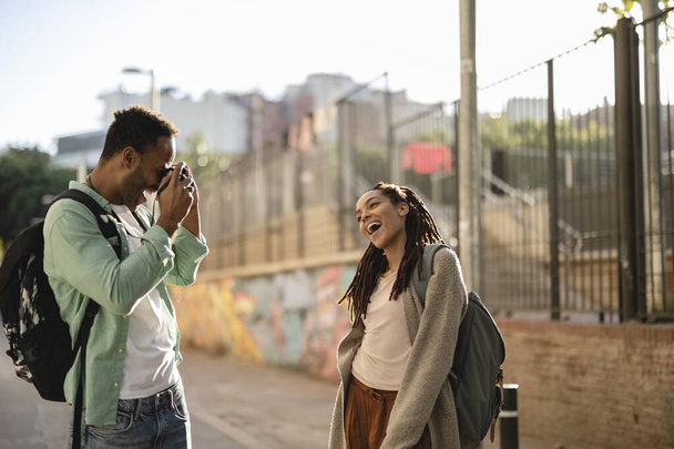 Para turystów bawiących się, robiących zdjęcia po mieście na wakacjach - Szczęśliwi przyjaciele śmiejący się razem na wakacjach - Ludzie i koncepcja wakacji - Zdjęcie, obraz