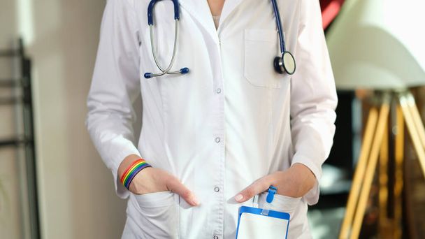 Immagine ritagliata di infermiera con braccialetto arcobaleno sulla mano. Supporto medico per la chirurgia di riassegnazione di genere. - Foto, immagini
