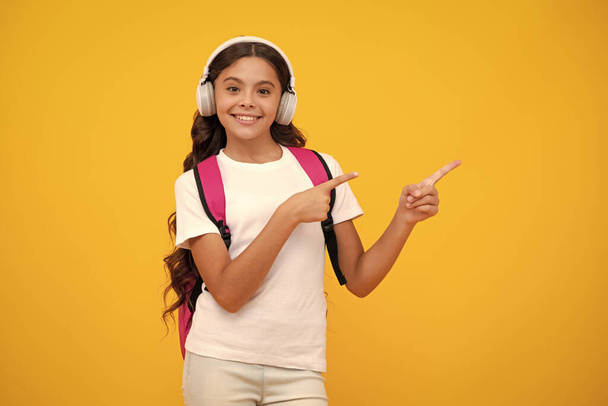 School girl in headphones on isolated studio background. School and music concept - Foto, Imagem