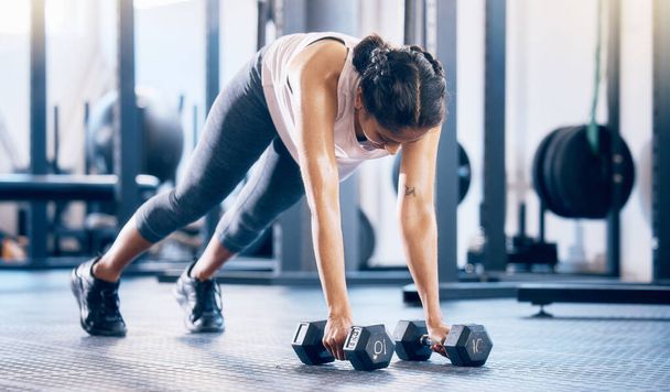 Dumbbell, fitness and training with woman in gym and push up for health, performance and challenge. Workout, wellness and strong with girl athlete and ground exercise for muscle, endurance and energy. - Photo, Image