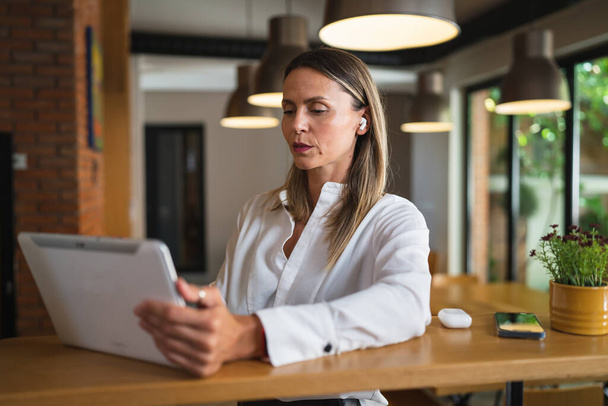 Одна взрослая женщина кавказская женщина-менеджер предприниматель работает с цифровой планшет, стоя за столом в помещении дома или на работе носить белые рубашки копировать пространство - Фото, изображение