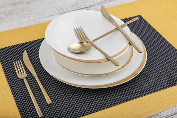 Plates and utensils, Plate, Bowl and golden cutlery on dining table, side view. Modern craft ceramic tableware, cutlery on the dining table. - Photo, Image